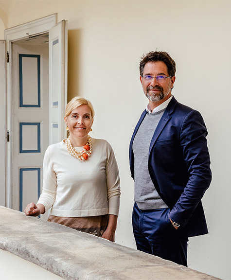 Mag. Šira Fera-Tischler MSc und Mag. Dr. Christof Pollak stehen im Atrium des Büros